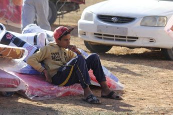 A displaced Libyan boy from the city of Sirte sits on a mattress distributed by the Red Crescent in Alarbaeen, Libya