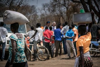 Two women walk past a group of public health outreach workers organised by MSF.