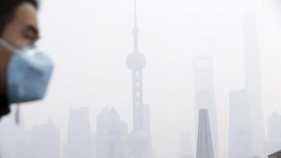 A man wearing a face mask walks on a bridge in front of the financial district of Pudong amid heavy smog in Shanghai, China