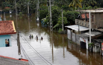 A group of men walk through a flooded road during a rescue mission in Nagoda village in Kalutara, Sri Lanka