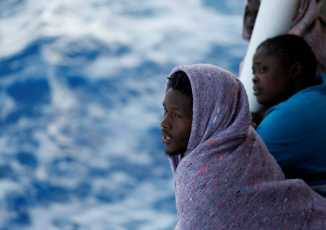 Migrants look out towards the Maltese island of Gozo as the Malta-based NGO Migrant Offshore Aid Station (MOAS) ship Phoenix makes its way towards Italy after rescue operations off the coast of Libya