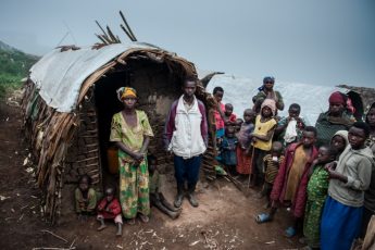 Nyirarukundo Anonciate, 39 (far left) standing next to her husband Saidi Olivier, 39, outside their shelter alongside their neighbours in Mpati village in North Kivu province in the Democratic Republic of the Congo.