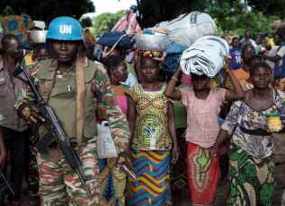 A Cameroonian United Nations peacekeeping soldier guards women fleeing the village of Zike as they arrive to the village of Bambara, Central African Republic.